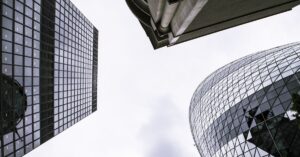 Low-angle view of modern glass skyscrapers against a pale sky